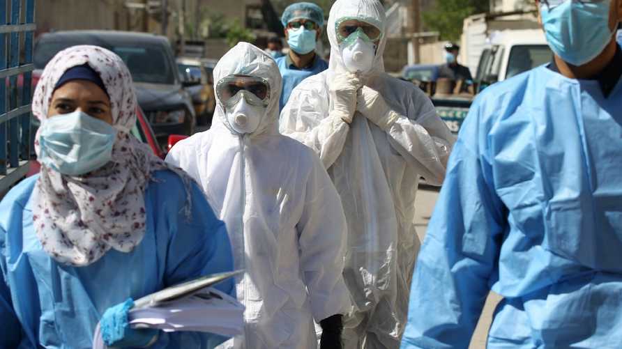Iraqi public hospital specialised doctors gather in a street before testing residents for COVID-19 in the capital Baghdad's suburb of Sadr City on April 2, 2020, as part of actions taken by the authorities against the spread of the novel coronavirus. - The process of examining citizens at their residences in Baghdad's eastern districts was launched in order to detect infection with the virus in the area where many cases were found to isolate patients and take them for treatment in public hospitals to limit the spread of the pandemic. (Photo by AHMAD AL-RUBAYE / AFP)