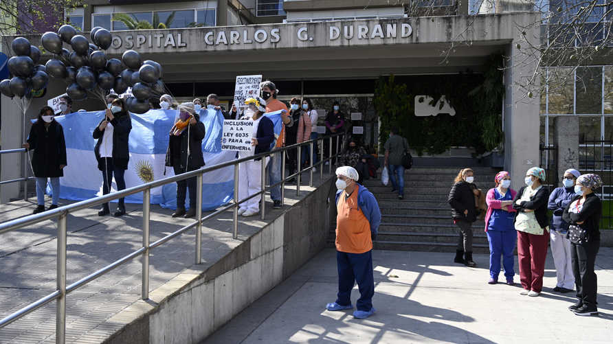 Health workers with an Argentinian flag and black balloons demand better working conditions and pay homage to nurse Grover Licona, who died from COVID-19, outside the Carlos G. Durand hospital in Buenos Aires, on August 18, 2020, amid the new coronavirus pandemic. (Photo by JUAN MABROMATA / AFP)