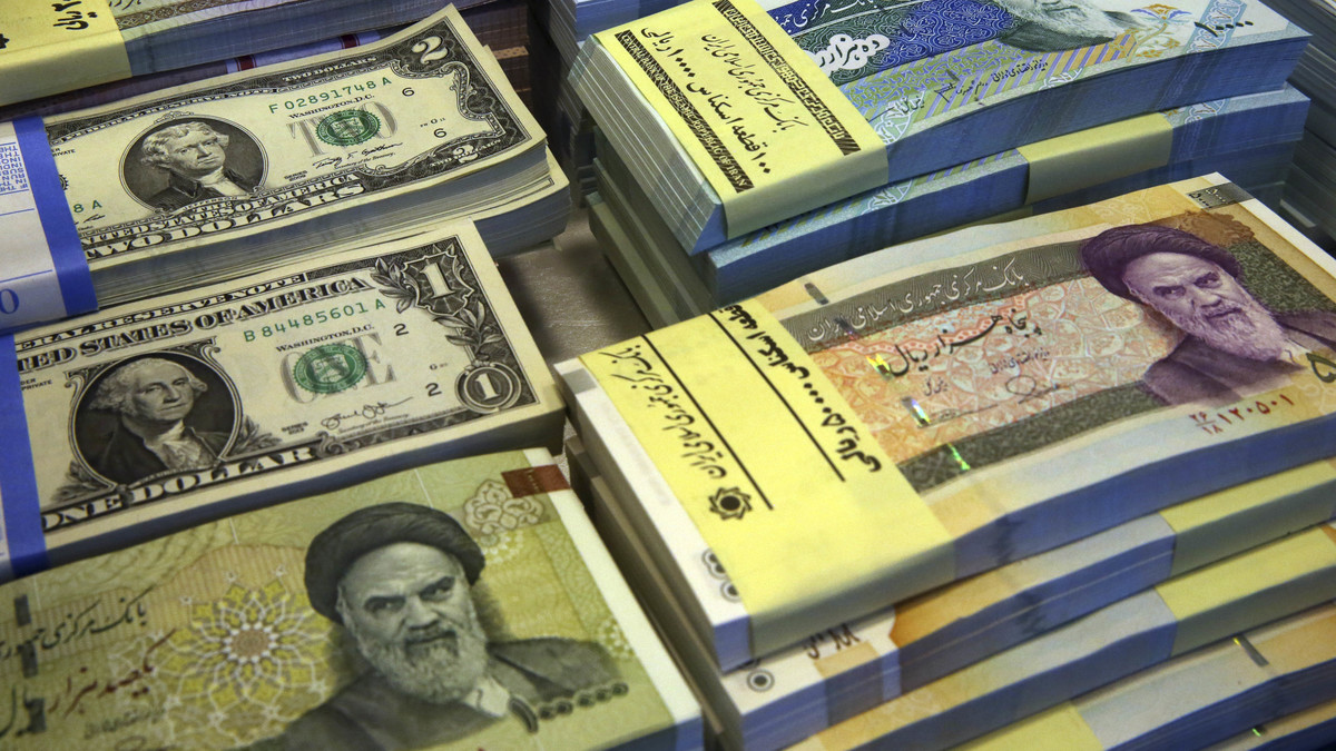 FILE--In this Saturday, April 4, 2015 file photo, Iranian and U.S. banknotes are on display at a currency exchange shop in downtown Tehran, Iran. Iran said Tuesday, Jan. 19, 2016,  it successfully transferred some of the billions of dollars' worth of frozen overseas assets following the implementation of the nuclear deal with world powers. But ordinary Iranians are still waiting to see how their daily lives will improve and how fast Iranian companies will gain access to financial markets worldwide. (AP Photo/Vahid Salemi,File)