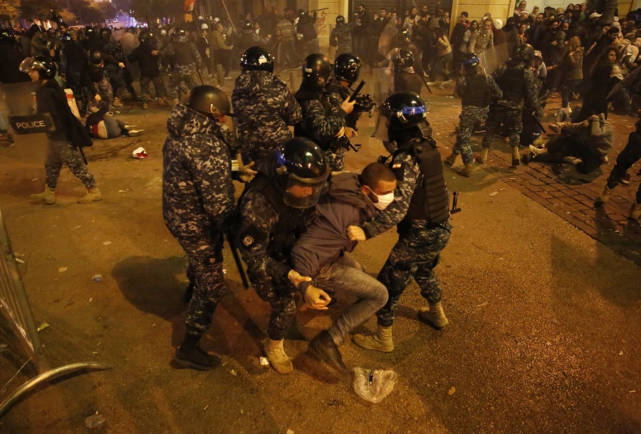 Riot police officers beat anti-government protesters during a protest near the parliament square, in downtown Beirut, Lebanon, Sunday, Dec. 15, 2019. Lebanese security forces fired tear gas, rubber bullets and water cannons Sunday to disperse hundreds of protesters for a second straight day, ending what started as a peaceful rally in defiance of the toughest crackdown on anti-government demonstrations in two months. (AP Photo/Hussein Malla)