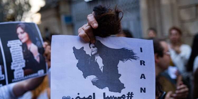 An Iranian woman living in Turkey, holds a ball of her cut hair and a poster of Mahsa Amini, during a protest outside the Iranian consulate in Istanbul on September 21, 2022, following the death of an Iranian Amini after her arrest by the country's morality police in Tehran. - Mahsa Amini, 22, was on a visit with her family to the Iranian capital Tehran, when she was detained on September 13, 2022, by the police unit responsible for enforcing Iran's strict dress code for women, including the wearing of the headscarf in public. She was declared dead on September 16, 2022 by state television after having spent three days in a coma. (Photo by Yasin AKGUL / AFP)